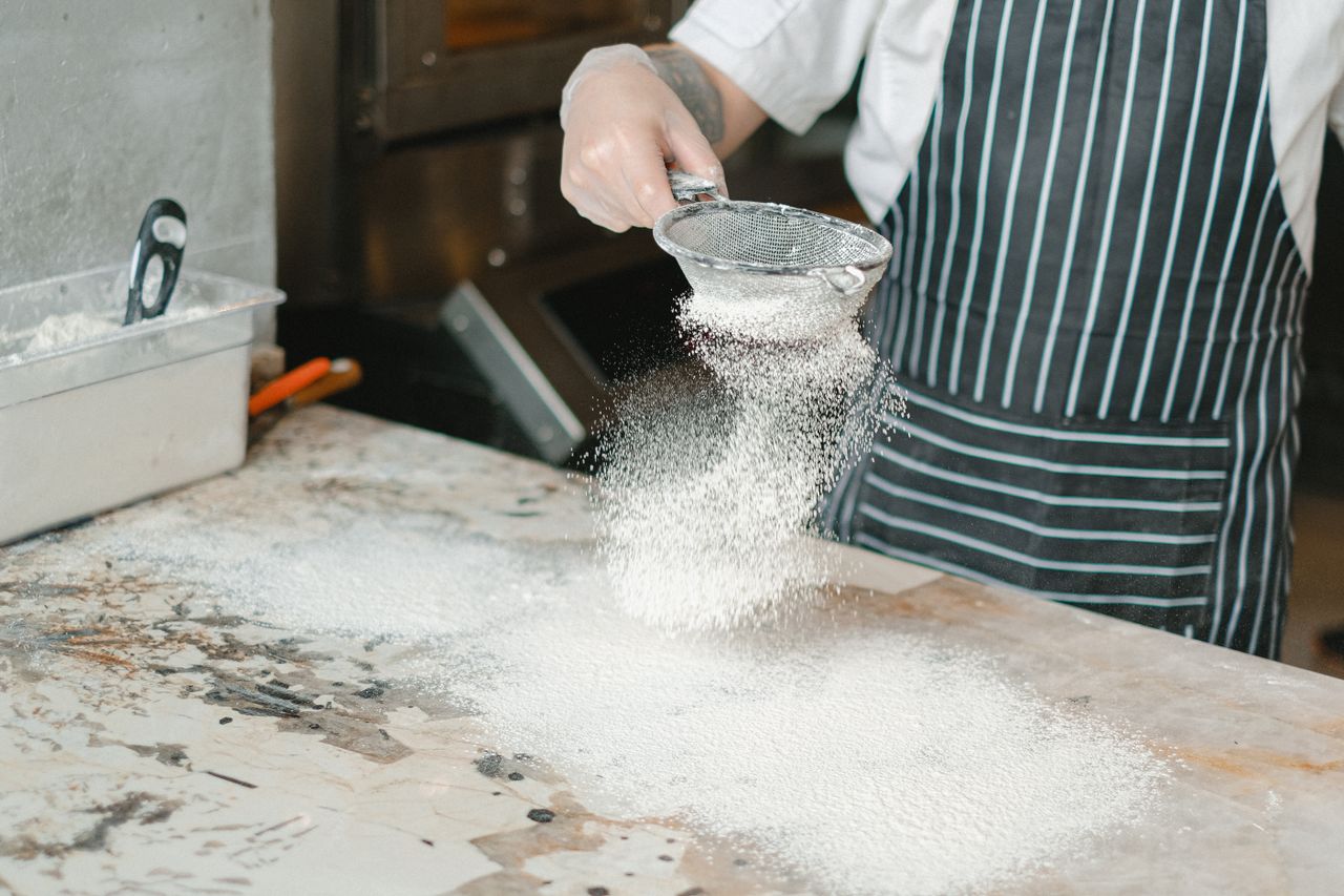 Baker dusting flour over shaped dough