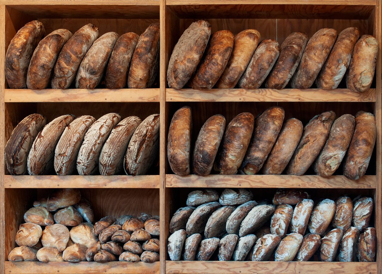 Round sourdough loaves cooling on a wooden bakery shelf